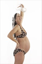Side view of pregnant woman pouring water on herself