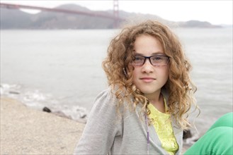 Caucasian girl sitting on beach near Golden Gate Bridge