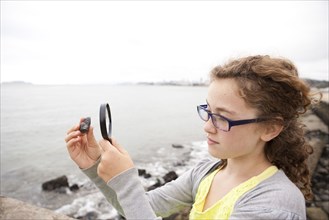 Caucasian girl examining stone with magnifying glass