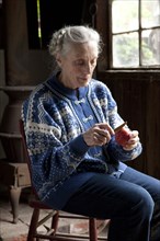 Older Caucasian woman peeling fruit in living room