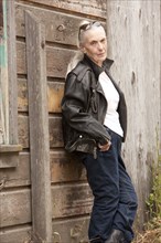 Older Caucasian woman leaning on wooden wall