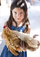 Mixed race girl holding chicken