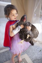 Mixed race girl holding chicken