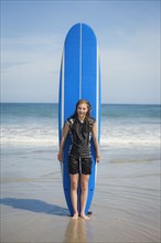 Caucasian girl holding paddleboard on beach