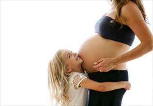 Caucasian girl hugging pregnant mother
