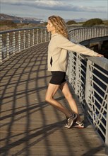 Caucasian woman stretching on footbridge