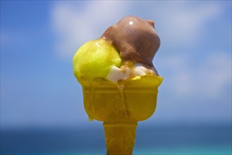 Close up of melting ice cream cone near ocean