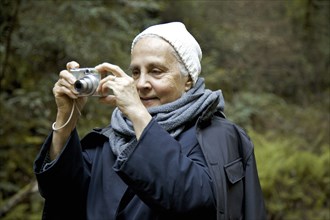 Close up of older woman photographing in forest