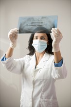 Indian dentist in surgical mask examining x-rays