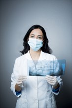 Indian dentist in face mask examining x-rays