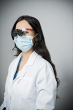 Indian dentist in surgical mask wearing binoculars