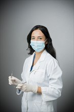 Indian dentist in surgical mask holding tools