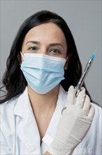 Indian dentist in surgical mask holding syringe