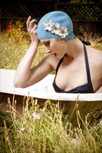 Woman wearing vintage swim cap in bathtub in backyard