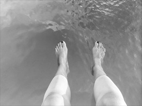 High angle view of legs of woman dangling in lake