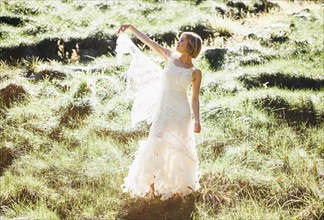Bride wearing wedding gown in rural field