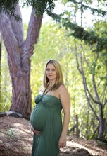 Smiling pregnant woman holding belly