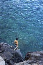 High angle view of woman climbing ladder into ocean