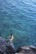 High angle view of woman climbing ladder out of ocean