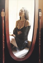 Mixed race woman in lingerie reflecting in mirror