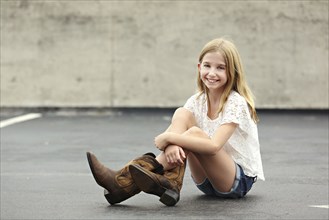 Smiling girl wearing cowboy boots in parking lot