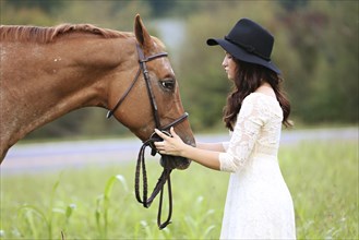 Woman petting horse in rural field