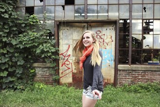 Smiling woman walking outside dilapidated building