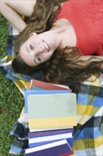 Woman laying with books on blanket