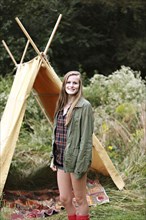 Smiling woman standing at camping tent