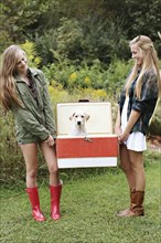 Close up of women carrying dog in vintage cooler
