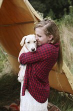 Woman cuddling dog near camping tent