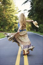 Teenage girl spinning on empty road