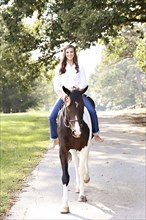 Woman riding horse on dirt road