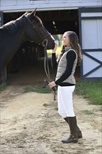 Equestrian woman petting horse at stable