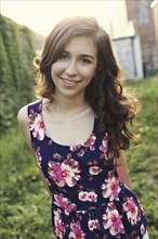 Smiling teenage girl standing in overgrown garden
