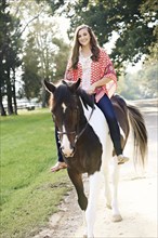Smiling woman riding horse on path