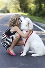 Close up of girl hugging dog on road