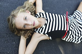 Close up of serious girl laying on pavement