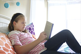 Close up of girl reading book on bed