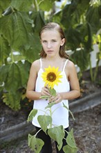 Close up of girl holding sunflower in garden