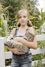 Serious girl holding cat in garden