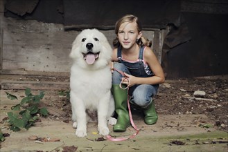 Girl crouching with dog in dilapidated shed