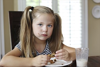 Girl eating cookie on table