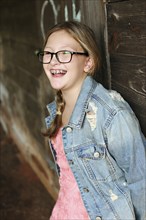 Smiling Caucasian girl leaning on wooden wall