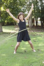 Smiling girl playing with plastic hoop in field