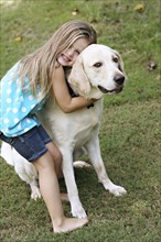 Smiling girl hugging dog in field