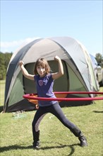 Caucasian girl playing with plastic hoop at campsite