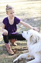 Caucasian girl petting dog in field