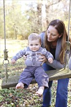 Mother and baby son on swing in backyard