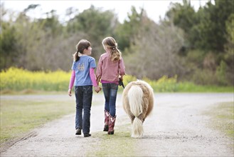 Caucasian girls walking pony on dirt path